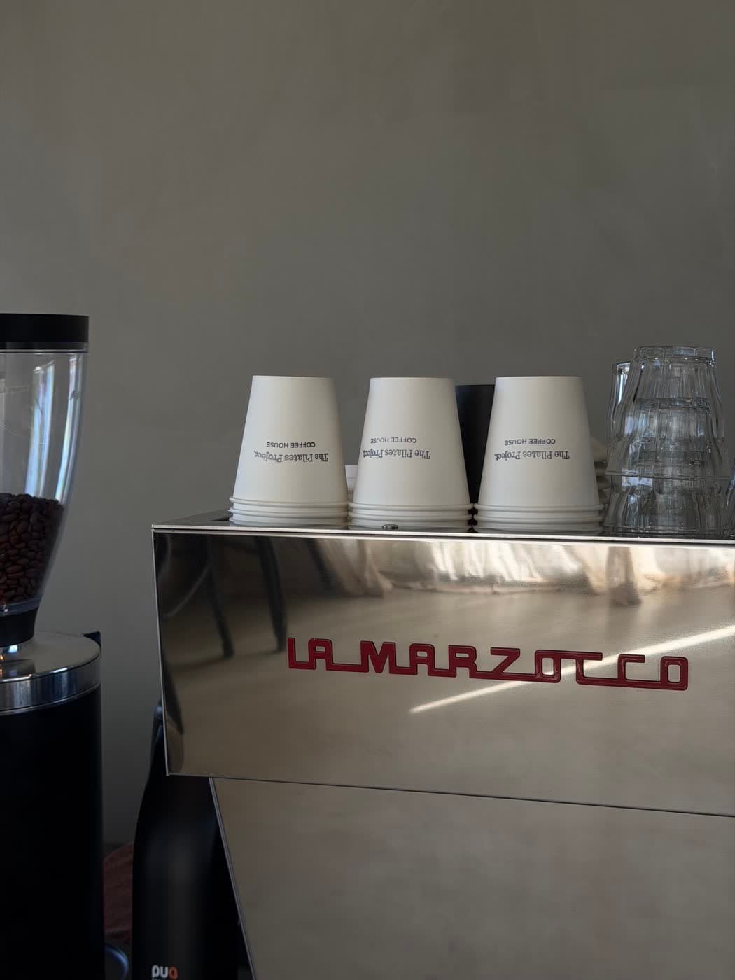 The Pilates Project cups stacked on the espresso machine at the TPP Coffee House