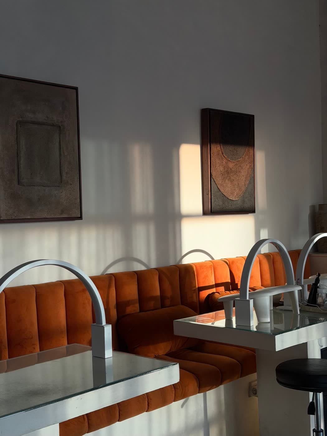 A sunlit nail bar with orange velvet seating at House of Orange